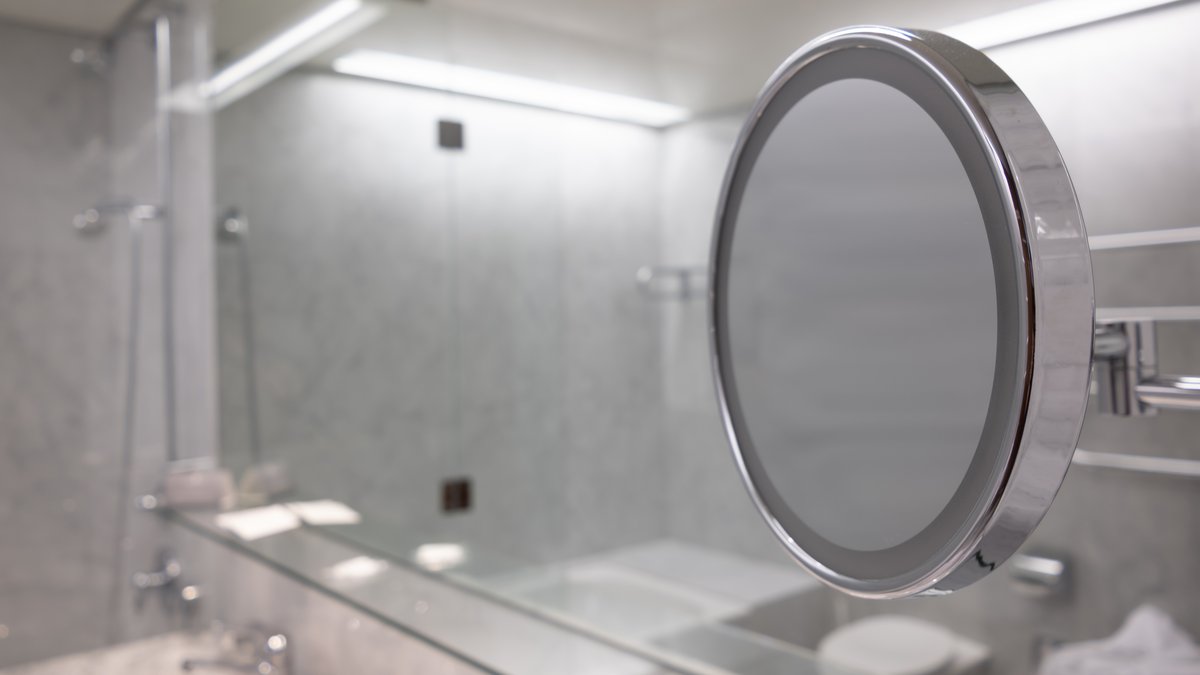 Detailed inspection of a luxury bathroom mirror checking for two-way observation glass and concealed camera lenses