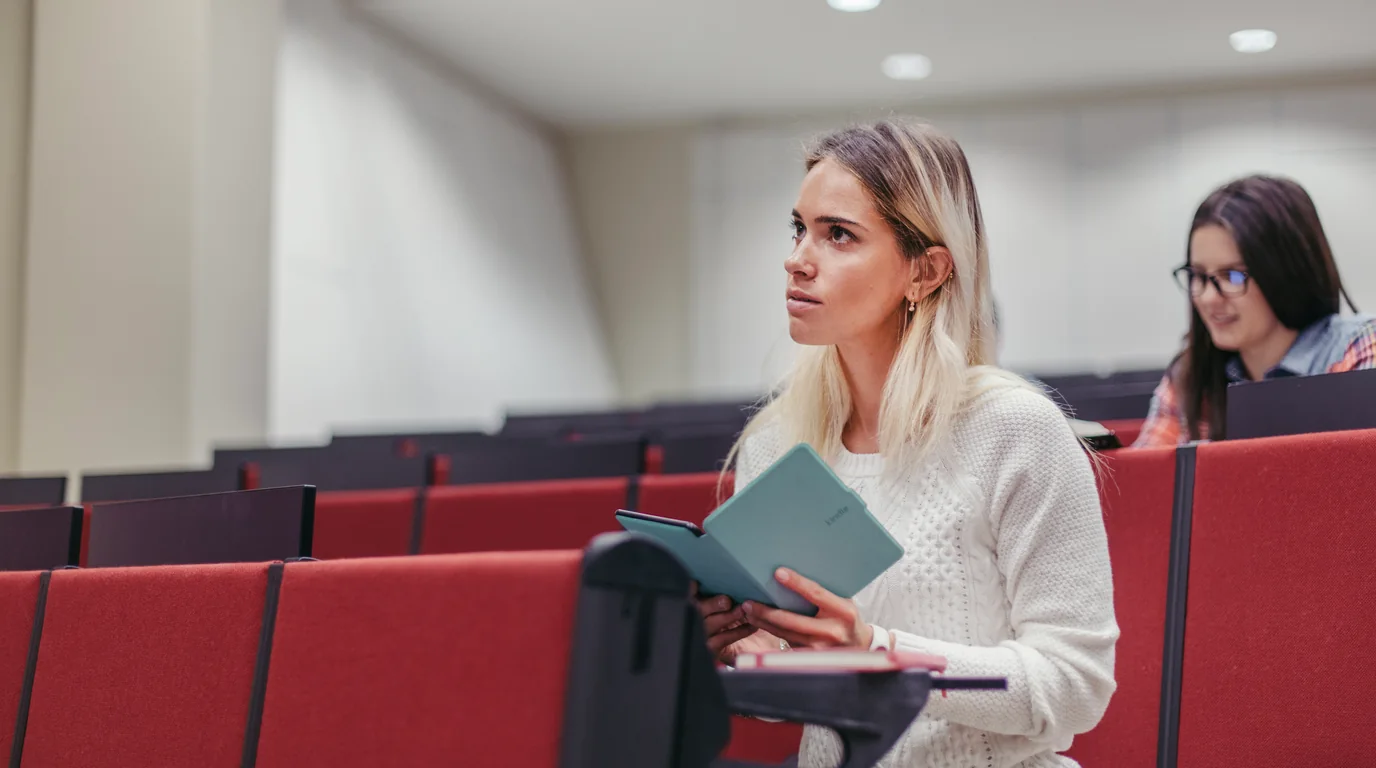 University student in a crowded lecture hall recording professor and taking structured notes