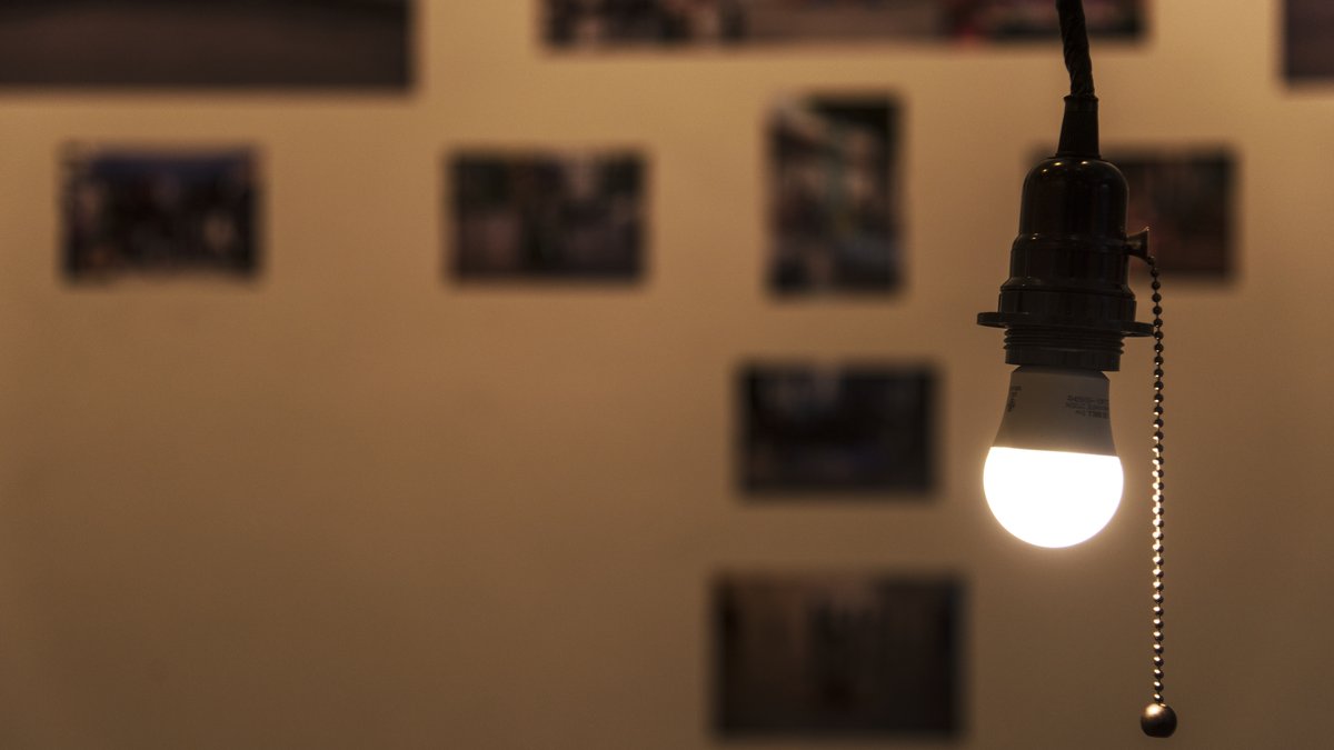Close-up of a modern light bulb fixture being inspected for panoramic spy cameras and hidden fisheye lenses
