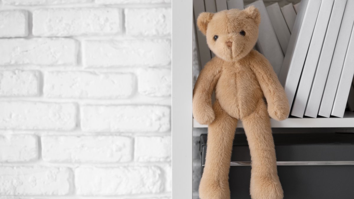 Cute plush teddy bear resting on a bedroom shelf in a cozy interior