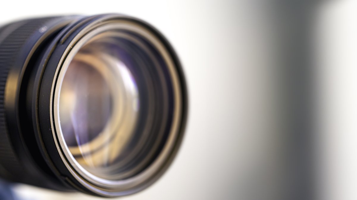Macro close-up of camera lens optics showing glass elements and optical light reflection