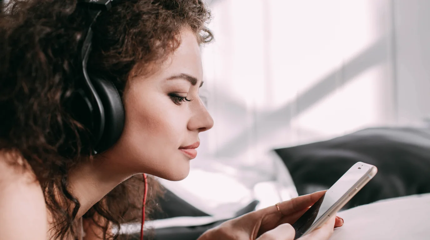 Professional listening to audio notes with earphones while reviewing transcripts on a smartphone