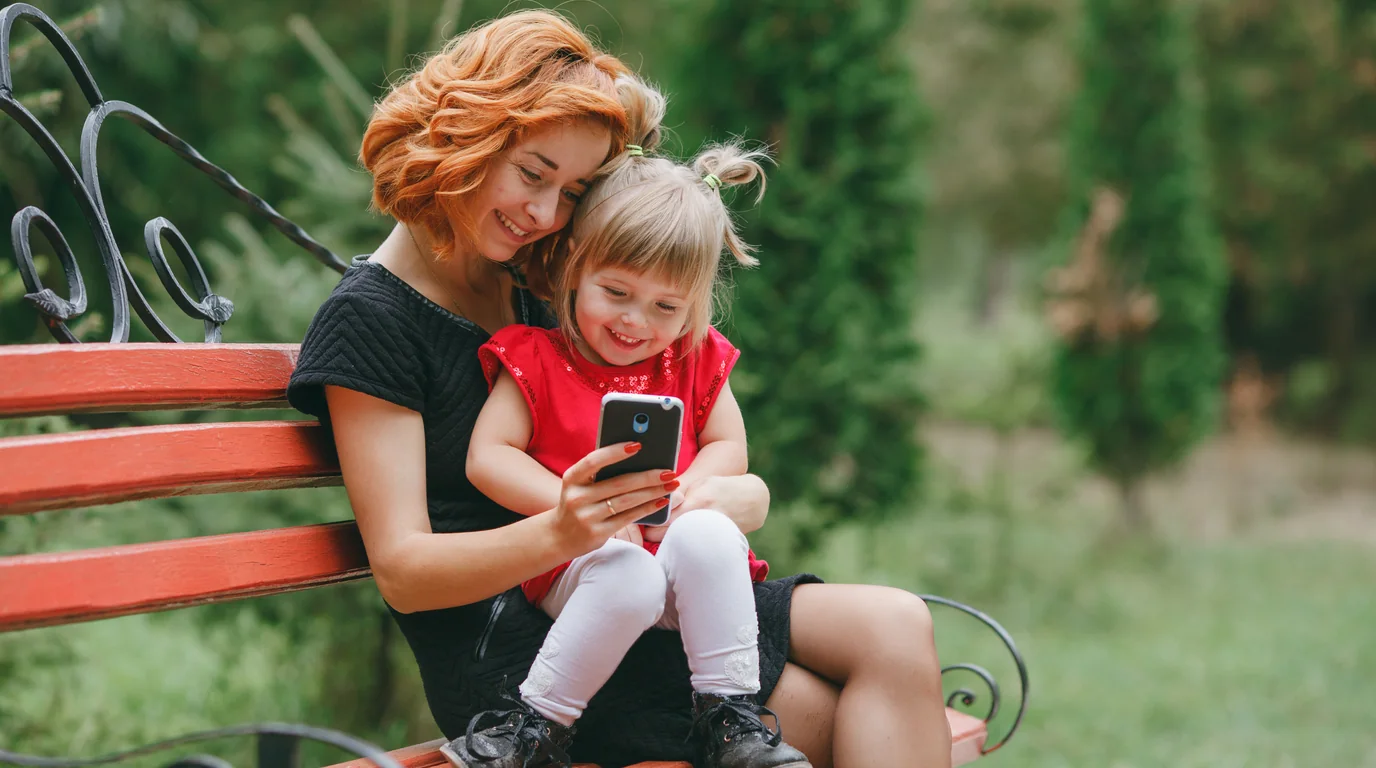 Padre captura recuerdos en el teléfono móvil con privacidad estética borrosa protegiendo la identidad del niño