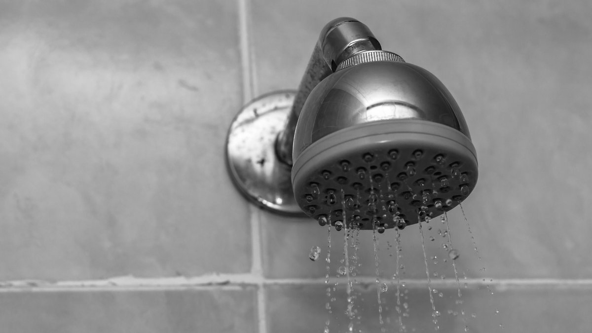 Close-up inspection of modern bathroom shower head checking for hidden spy camera lenses