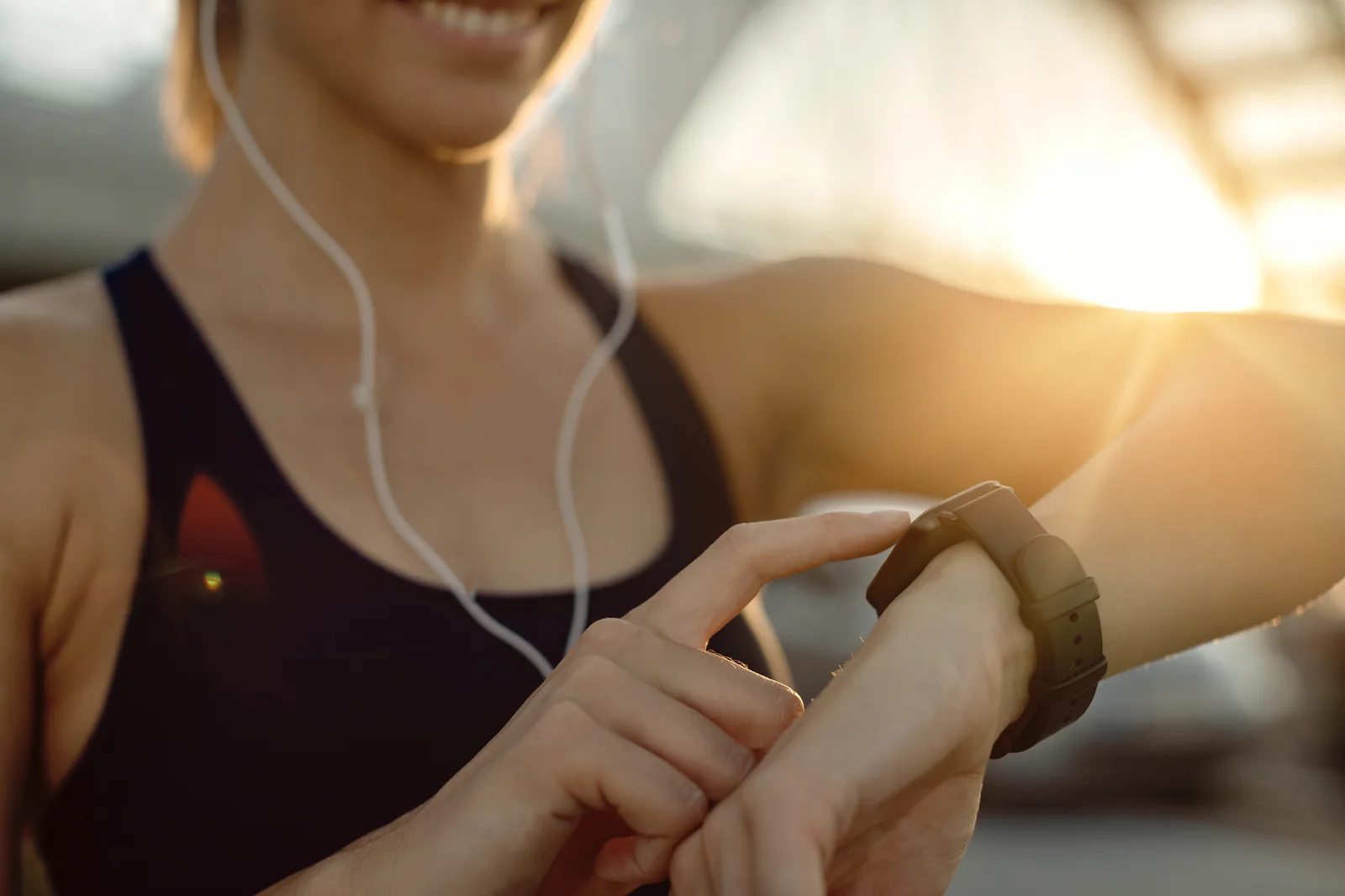 Closeup of athletic woman inspecting fitness tracker and smartphone pedometer calibration at sunset outdoors