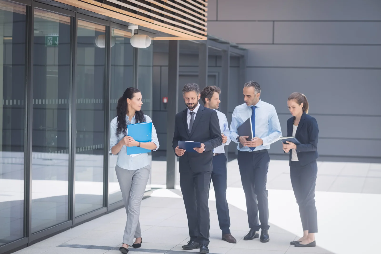 Group of business colleagues walking outside office building during corporate walking meeting